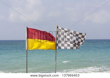 black and white checkered flag and surf lifesaving flag on beach photo