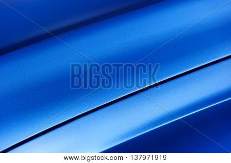 Surface of blue sport sedan car metal hood, part of vehicle bodywork, steel gradient line pattern