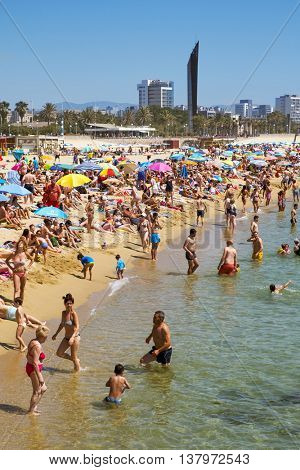 BARCELONA, SPAIN - JULY 10: People sunbathing at Platja del Bogatell beach on July 10, 2016 in Barcelona, Spain. This busy beach is mainly frequented by the locals