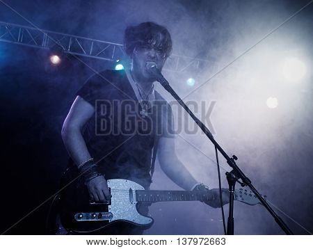 Silhouette of guitar player on stage. Dark background, smoke, spotlights