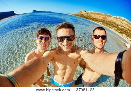 young happy couple friends on the beach taking selfie on sea background. Balos beach, Crete, Greece.