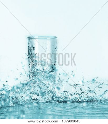Pouring water into glass on light background