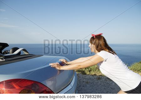 Young woman push the car runs out of gas.