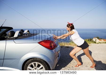 Young woman push the car runs out of gas.
