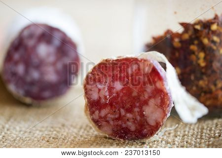 Slice Of Hot Salami With Crushed Hot Pepper On A Background