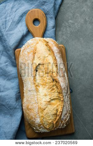 Freshly Baked Hand Crafted Rustic Bread Loaf On Cutting Board Dark Stone Background. Authentic Rusti