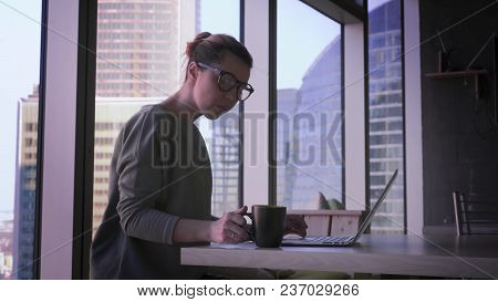 Young Business Woman In Glasses Is Working On Laptop In Office. Beautiful Female With Computer In Bu