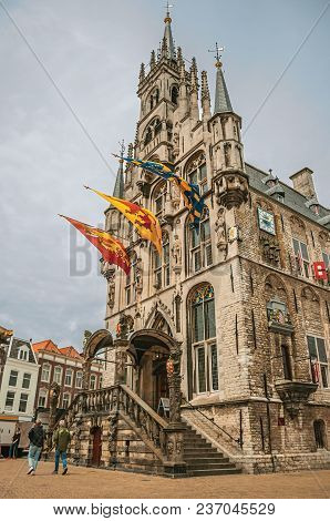 Gouda, Southern Netherlands - June 29, 2017. People At Market Square With Gothic City Hall And Flags