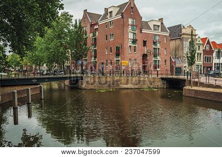 Gouda, Southern Netherlands - June 29, 2017. Walled Canal With Bascule Bridge, Trees And Brick Build