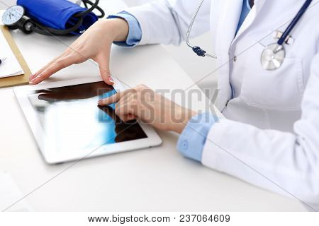 Woman Doctor Using Tablet Computer While Sitting At The Desk In Hospital Closeup. Cardiologist Check