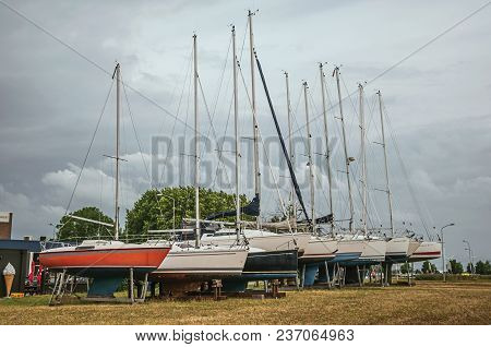 Several Sailboats Collected In Brackets For Repair In An Open Area On Cloudy Day At Drimmelen. A Lov