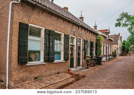 Charming And Quiet Alley With Brick Rustic Houses And Greenery In Cloudy Day At Drimmelen. A Lovely 