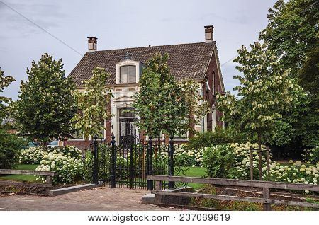 Drimmelen, Southern Netherlands - June 30, 2017. Charming Brick Rustic House With Flowered Garden An