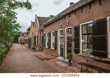 Charming And Quiet Alley With Brick Rustic Houses And Greenery In Cloudy Day At Drimmelen. A Lovely 