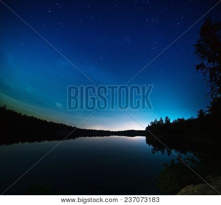 Lake At Night With Amazing Starry Sky And Reflections In The Water. Natural Outddors Travel Dark Bac