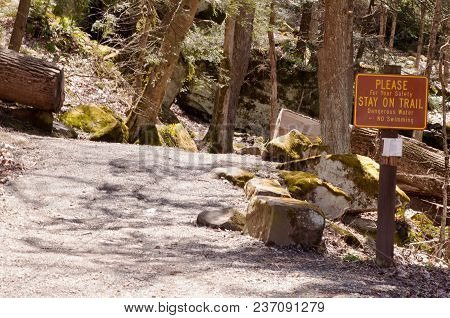 A Warning Sign Next To A Hiking Trail In The Forest
