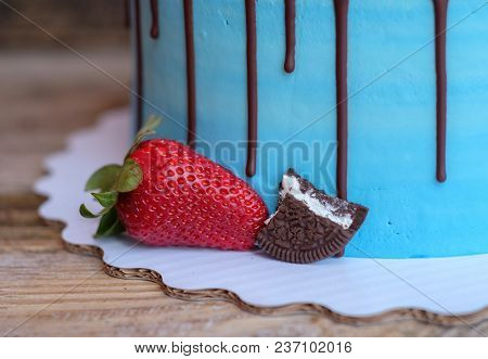 Beautiful Homemade Cake With Blue Cream And Chocolate Glaze, Decorated With Strawberries And Blueber