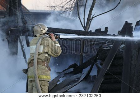 Firefighter Extinguishes  Fire. Fireman Holding  Hose With Water, Watering  Strong Stream Of Burning