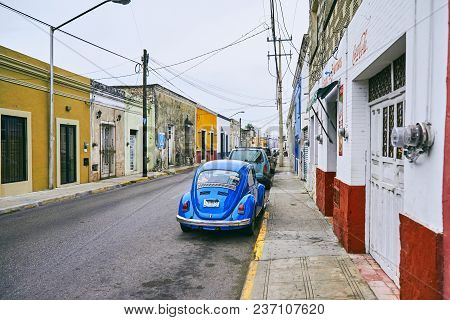 Merida / Yucatan, Mexico - June 1, 2015: The Vintage Blue Car Parking Infront Of The Old Red Buildin