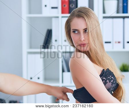 Man's Hand Pulls Bra Out Of The Beauitiful Secretary In Office Background. Flirt Or Harassment Conce