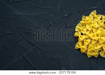 Farfalle Raw Farfallini Background With Pasta On A Black Background With A Side. A View From The Top