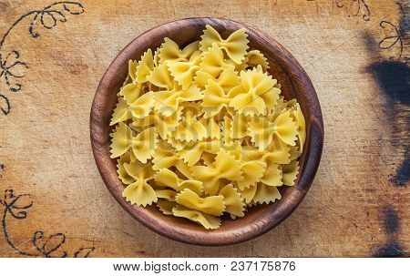 Farfalle Raw Farfallini Pasta In A Wooden Bowl On A Cutting Wooden Board, Texture Background, In The