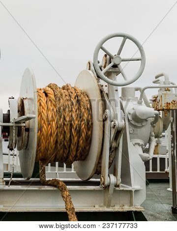 Winch With Orange Rope On A Ferry, White Cloudy Backgrond.