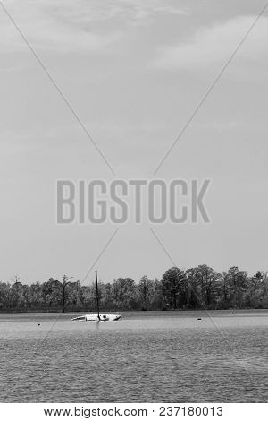 A Black And White Photo Of A Capsized Boat In A Waterway