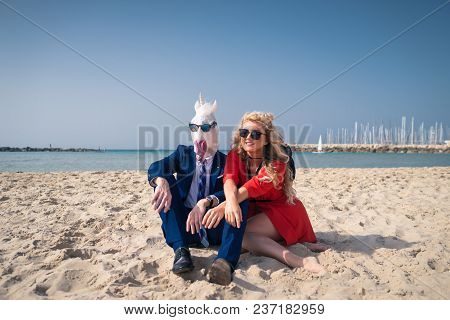 Unusual Couple Are Sunbathing On The Beach And Enjoys Vacation. Comical Man In Elegant Suit And Funn