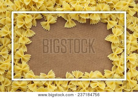 Farfalle Raw Farfallini Background Of Pasta. A Textured Wooden Cutting Board. Close-up View From The