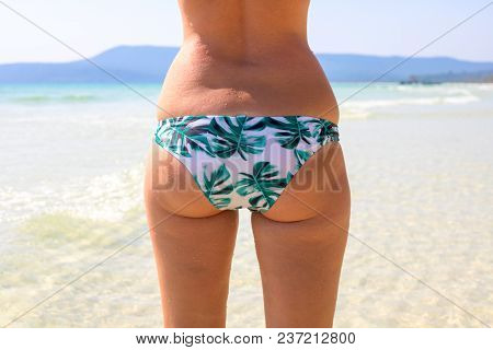 Woman In Bikini On Sunny Beach. White Sand Sea Shore. Relaxing Sea View With Female Body. Rear Persp