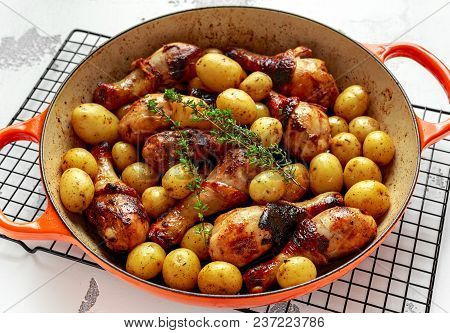 Oven Baked Chicken Drumsticks And New Baby Potatoes With Thyme In Pan, Ready To Serve.