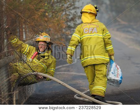 Melbourne, Australia - April 13, 2018: Fire Fighters At A Fence During A Bush Fire In An Suburban Ar
