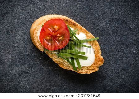 Open faced sandwich canape or crostini on dark stone background closeup. Top view. Vegetarian tartarine.