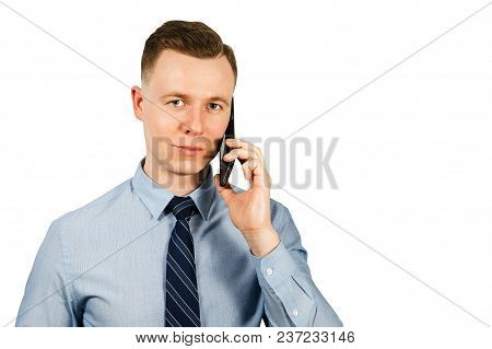 Portrait Of Young Businessman Dressed In Blue Shirt And Tie Talking On The Mobile Phone, Isolated On