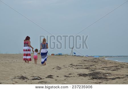 Mom And Daughter And Sister Walk On The Sandy Beach