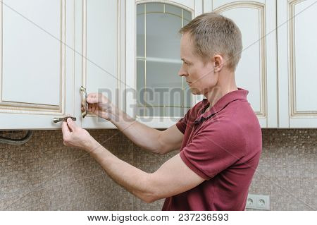 Installation Of Kitchen Furniture. The Man Is Putting Handles To Door Cabinets.