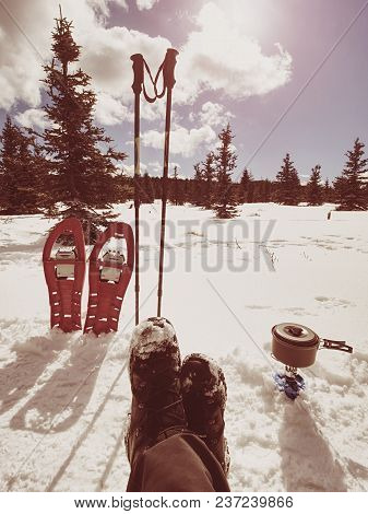 Lunch Time During Winter Trail. Camping On Snow And Cooking. Red Snowshoes And Trekking Poles Stand 