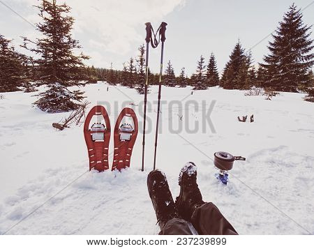 Lunch Time During Winter Trail. Camping On Snow And Cooking. Red Snowshoes And Trekking Poles Stand 