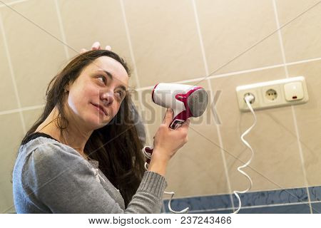 Young Woman With Brown Hair Drying Hair With Electric Blowdryer At Home.