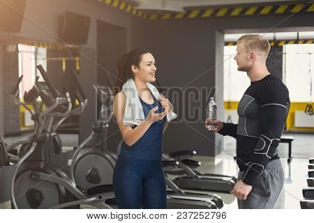 Fitness Couple Having Rest, Drinking Water At Gym. Smiling Woman And Man With Plastic Bottle, Talkin