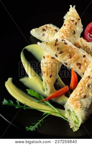 Puff Pastry With Spinach And Cheese Filling On A Black Plate And Black Background.