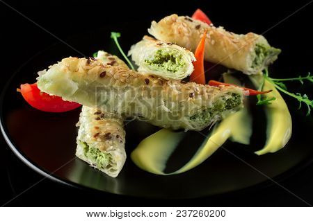 Puff Pastry With Spinach And Cheese Filling On A Black Plate And Black Background.