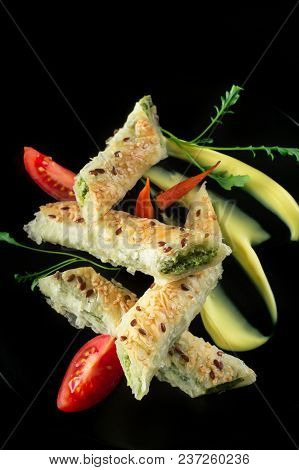 Puff Pastry With Spinach And Cheese Filling On A Black Plate And Black Background.