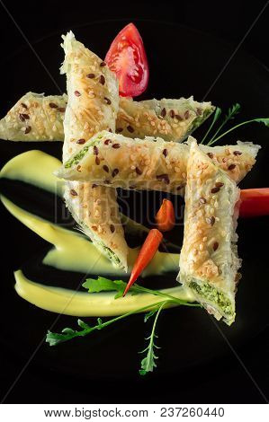 Puff Pastry With Spinach And Cheese Filling On A Black Plate And Black Background.