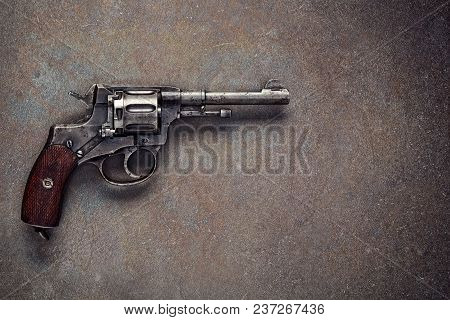 Old revolver on  vintage dark concrete background.