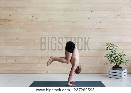 Sporty Man Practices Yoga Handstand Asana Adho Mukha Vrikshasana At The Yoga Studio. Balance Exercis