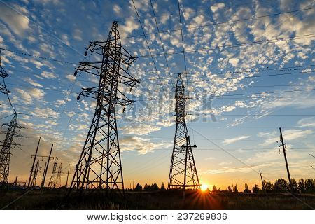 High Voltage Power Line Supports At Sunset.