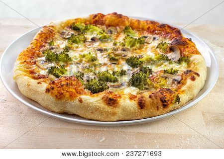 Home Baked Pizza With Brocolli , Mushrooms And Mozzarella Cheese On Wooden Baking Board