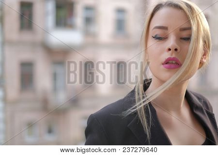 Portrait Of A Young Woman In A Black Suit Close-up Against A Background Of A Blurry City In The Rays